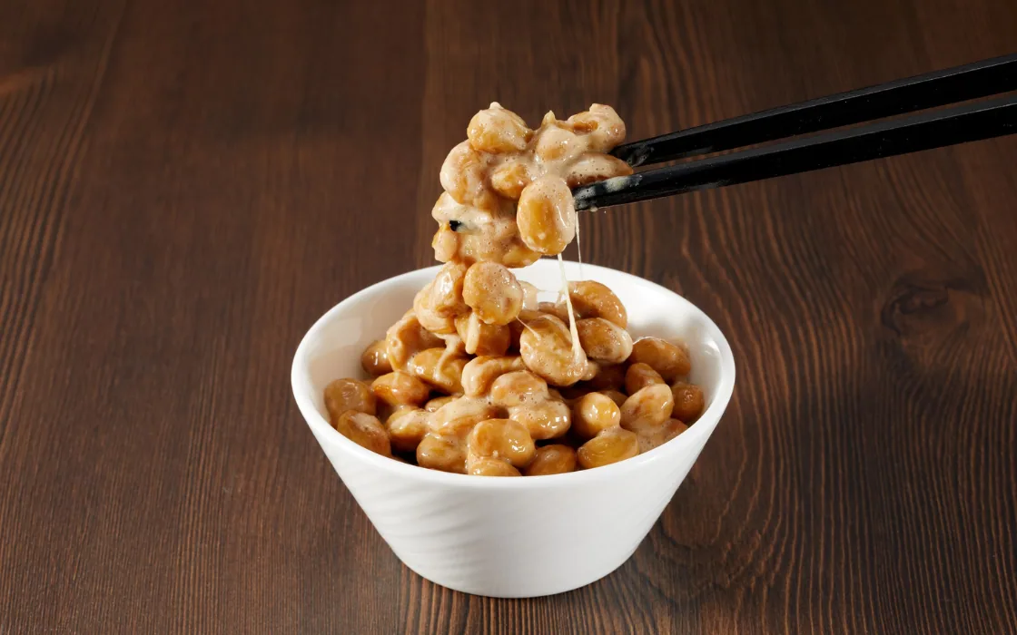 Schale mit Natto, fermentierten Sojabohnen, die mit Stäbchen angehoben werden