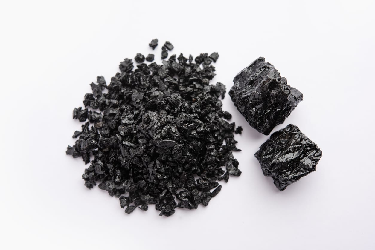 Schwarze Shilajit-Harzbrocken und -Stücke auf weißem Hintergrund