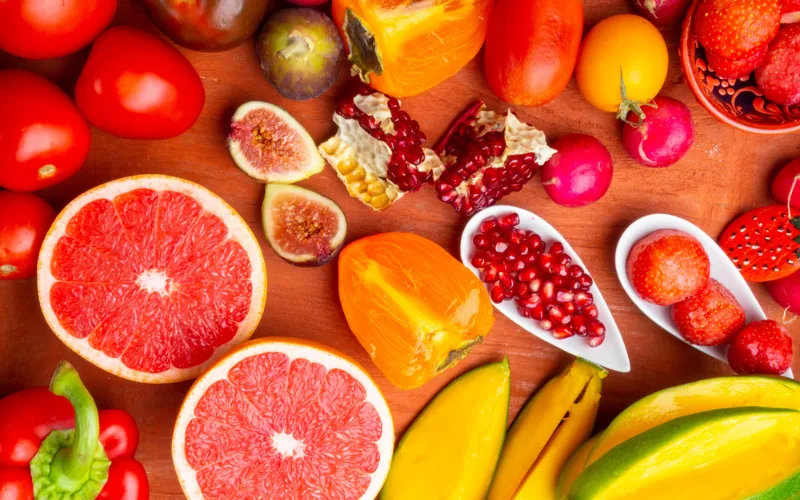 Rotes und orangefarbenes Obst und Gemüse wie Grapefruit, Granatapfel, Tomaten und Paprika