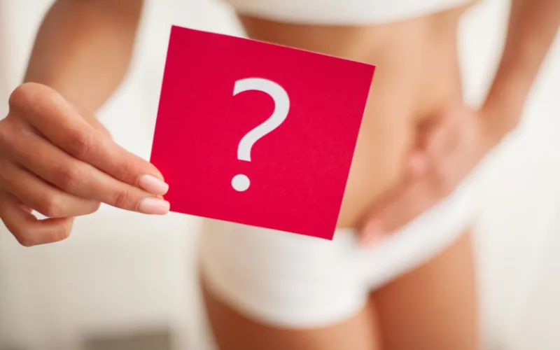 Frau hält eine rote Karte mit einem Fragezeichen vor ihren Bauch