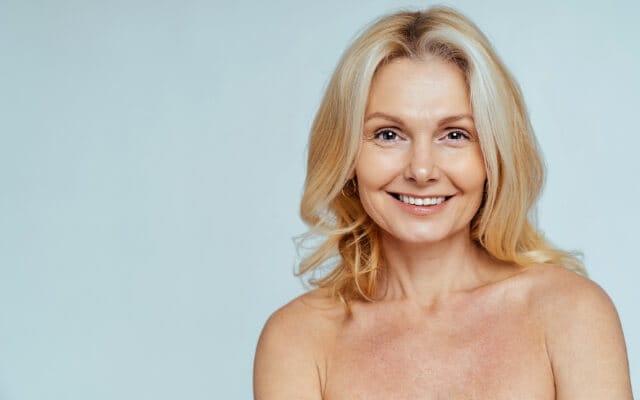Lächelnde Frau mit glatter Haut vor hellem Hintergrund