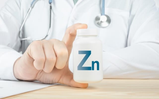 Arzt hält eine weiße Dose mit dem Zink-Symbol Zn in der Hand
